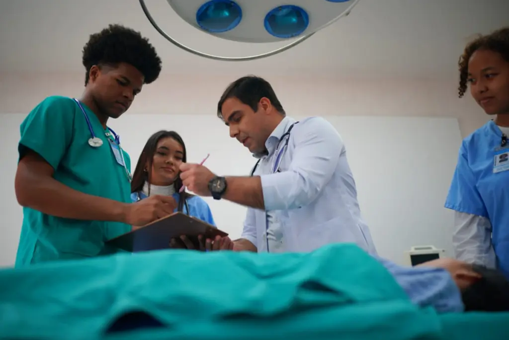Estudantes de medicina recebendo instrução de médico durante atendimento ao paciente no estágio em medicina