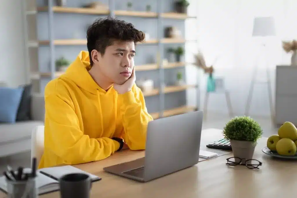 rapaz pensativo diante de computador