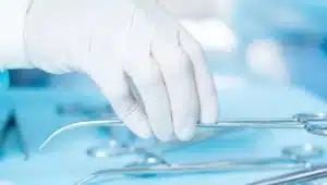 mão de cirurgião com luva pegando tesoura