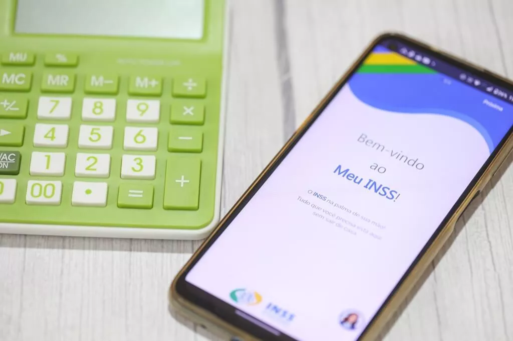 calculadora ao lado de celular com app do inss